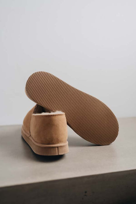 Close up  of Tan coloured loafer style sheepskin slipper showing the ribbed underside of the PVA sole