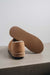 Close up  of Tan coloured loafer style sheepskin slipper showing the ribbed underside of the PVA sole