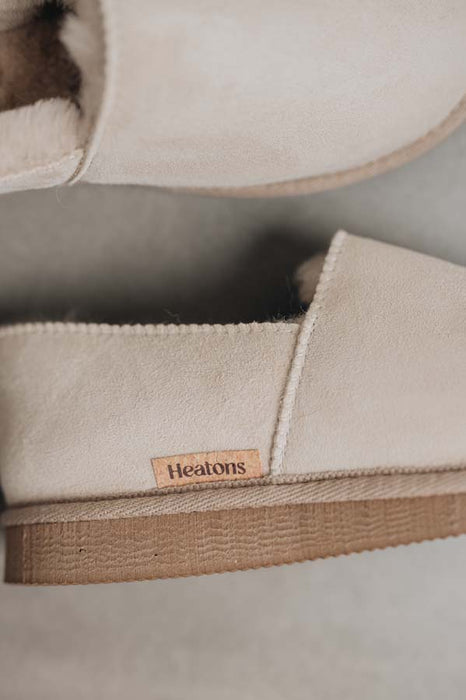 Close up of Vanilla coloured loafer style sheepskin slipper with natural cork label showing the Heatons brand