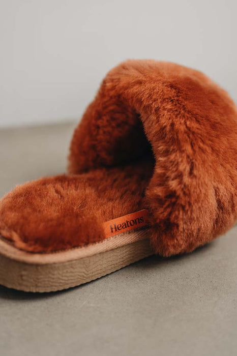 Close up view of Veronica Rust Sheepskin Slippers with Heatons label detail on Concrete Surface