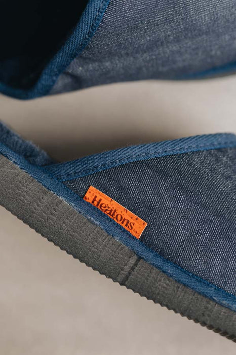 Close up of denim covered slip on style sheepskin slipper with orange cork label showing the Heatons brand