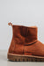 Close-up of a the back of a rust coloured sheepskin boot with 'Heatons' branding and a chunky sole.
