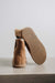 Tan sheepskin ankle boot slipper with textured rubber sole on a light grey stone background