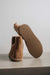 Tan sheepskin boot with textured rubber sole on a light grey background